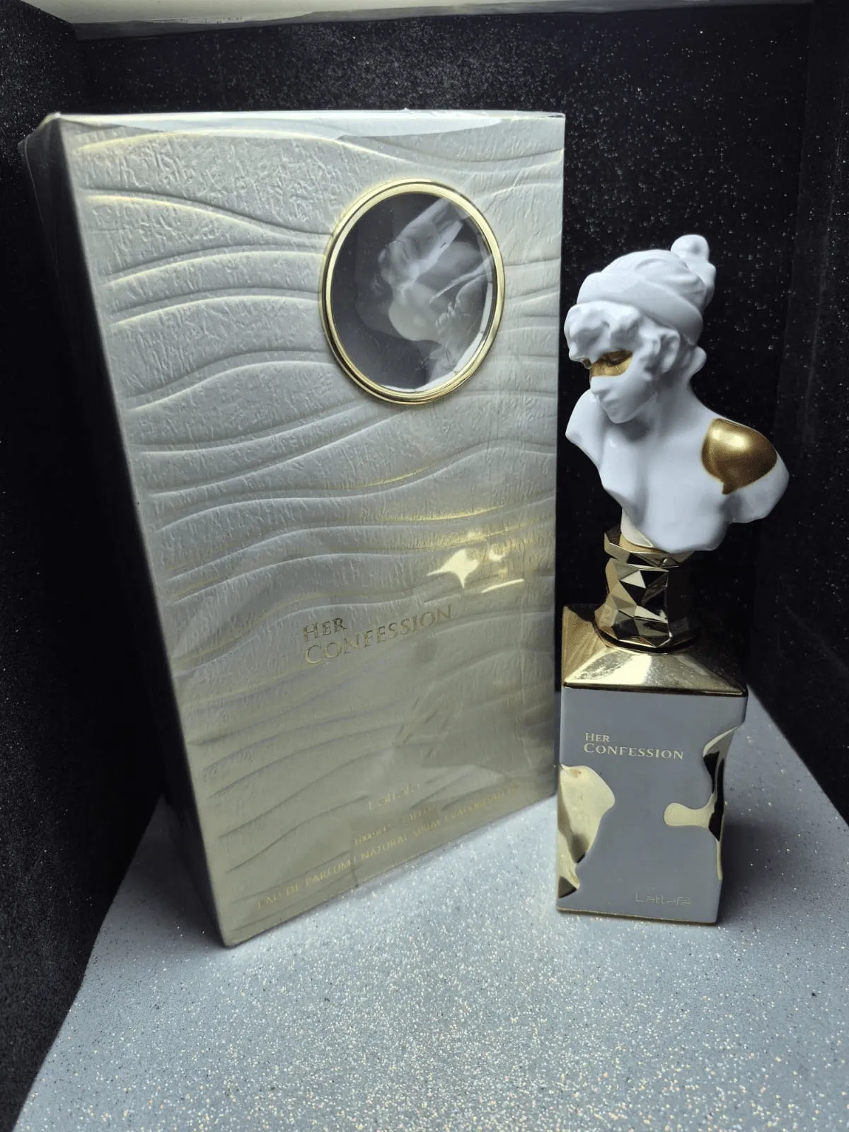 Perfume árabe Lattafa Her Confession para mujer en frasco con forma de busto de mármol blanco y caja original.
