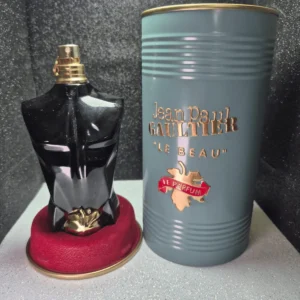 Perfume Jean Paul Gaultier Le Beau Le Parfum para hombre en frasco de torso negro con hoja dorada y lata.